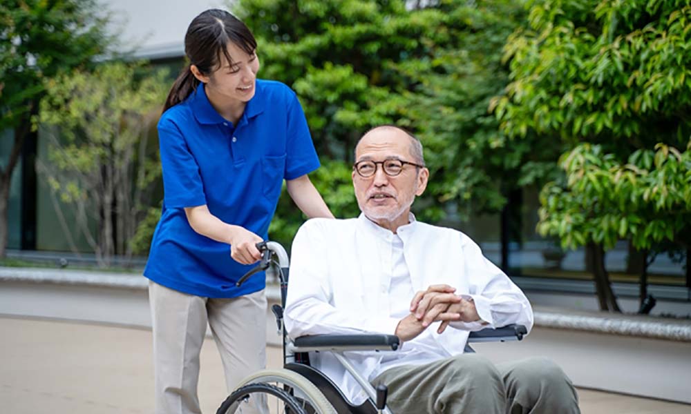 介護士が車椅子を押して笑顔で散歩する様子